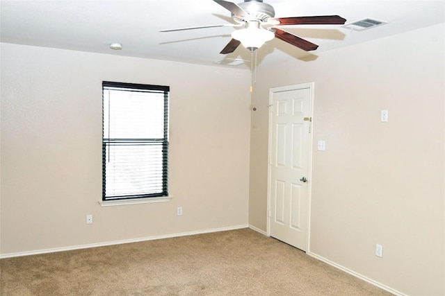 empty room featuring light carpet, ceiling fan, visible vents, and baseboards