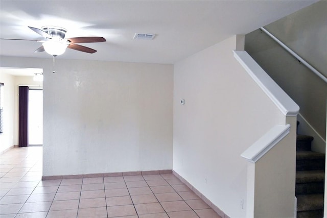 empty room featuring stairway, visible vents, a ceiling fan, and light tile patterned flooring