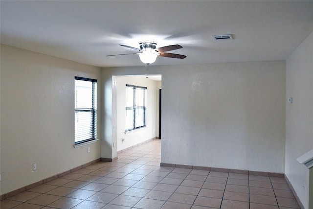 unfurnished room featuring light tile patterned floors, baseboards, visible vents, and a ceiling fan