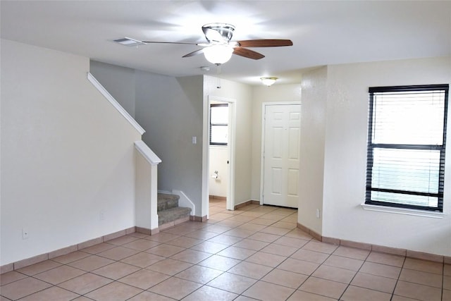 unfurnished room featuring light tile patterned floors, visible vents, baseboards, a ceiling fan, and stairway