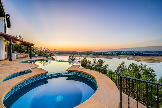 1208 Watercliffe Dr, Lago Vista, TX 78645 - pool at dusk featuring exterior kitchen, a patio area, a water view, and an in ground hot tub