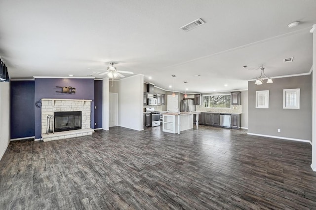 unfurnished living room featuring dark wood-style floors, a brick fireplace, visible vents, and crown molding