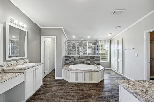 bathroom with a tile shower, ornamental molding, wood finished floors, and visible vents