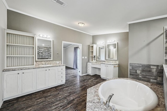 full bath featuring a garden tub, two vanities, visible vents, ornamental molding, and wood finished floors