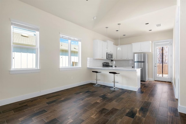 kitchen with appliances with stainless steel finishes, dark wood finished floors, and a peninsula