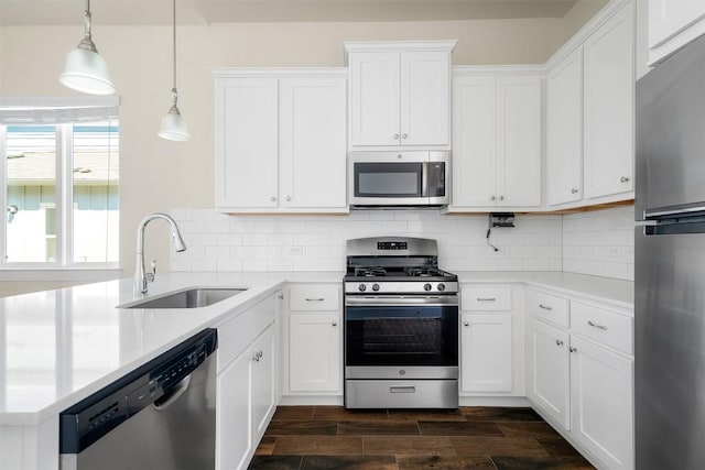 kitchen with wood finish floors, stainless steel appliances, tasteful backsplash, light countertops, and a sink