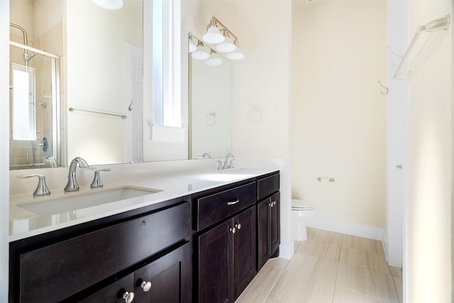 bathroom featuring toilet, a shower stall, double vanity, and a sink