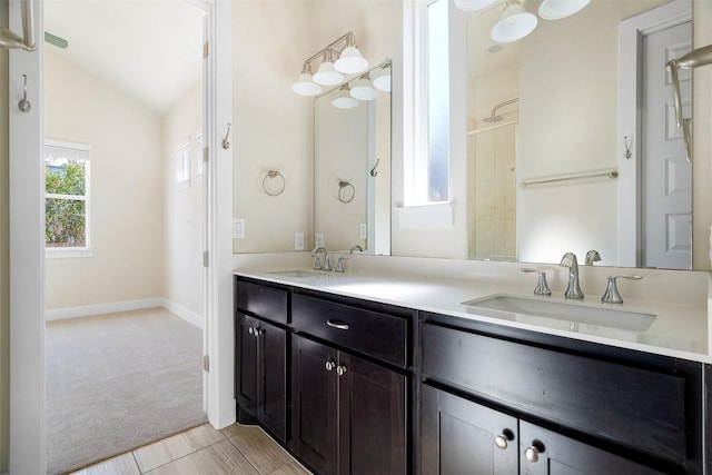 bathroom with lofted ceiling, double vanity, baseboards, and a sink