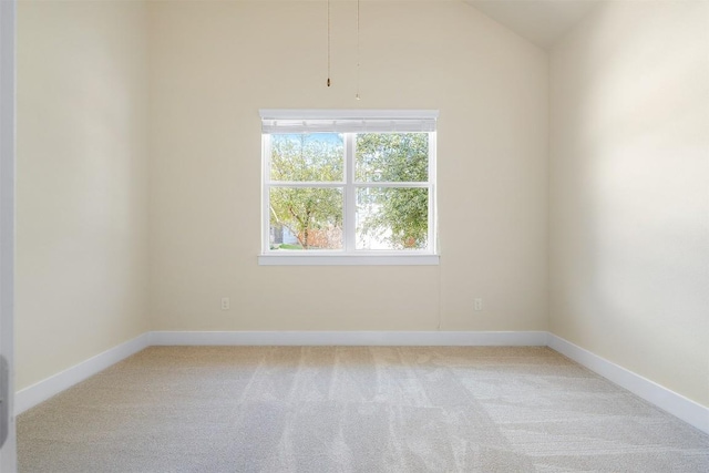 empty room featuring baseboards, vaulted ceiling, and light colored carpet