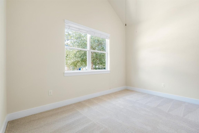 unfurnished room featuring light carpet, baseboards, and lofted ceiling