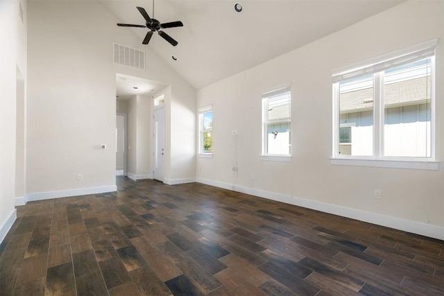 empty room with baseboards, visible vents, dark wood finished floors, a ceiling fan, and high vaulted ceiling