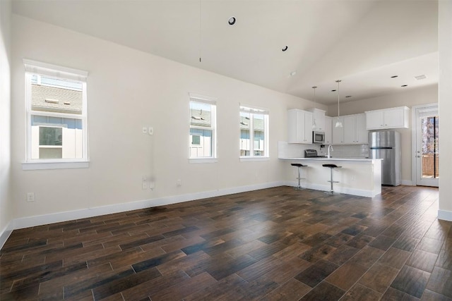 kitchen featuring appliances with stainless steel finishes, a kitchen breakfast bar, dark wood-style flooring, a peninsula, and light countertops