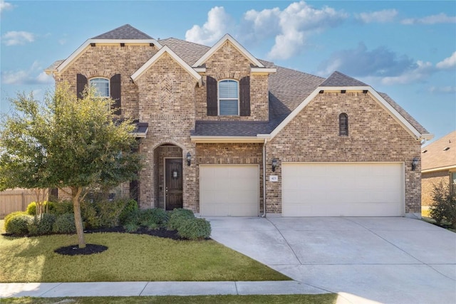 view of front of house with driveway, roof with shingles, an attached garage, a front lawn, and brick siding