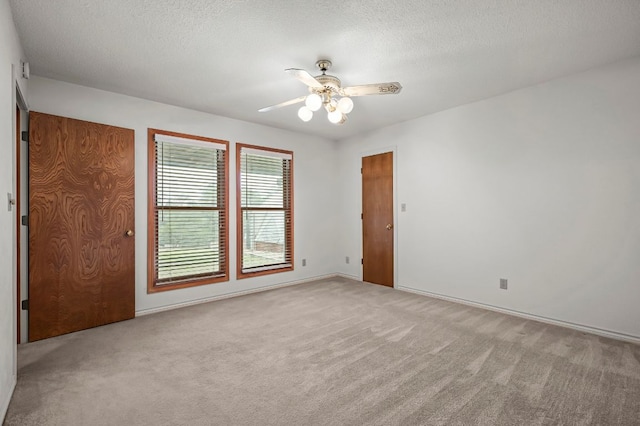 carpeted empty room featuring ceiling fan and a textured ceiling