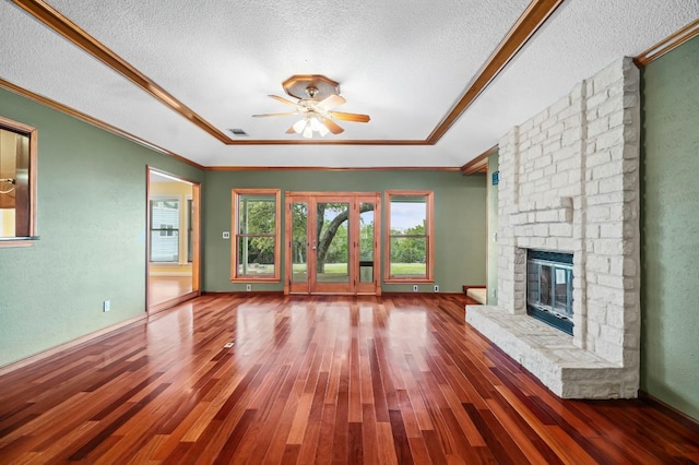 unfurnished living room with a large fireplace, a textured ceiling, ornamental molding, and wood finished floors