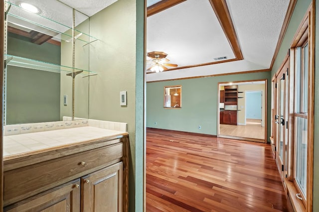 bathroom with visible vents, a ceiling fan, wood finished floors, crown molding, and a textured ceiling