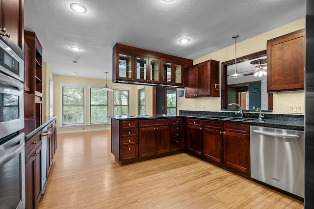 kitchen with decorative light fixtures, light wood finished floors, a sink, dishwasher, and a peninsula