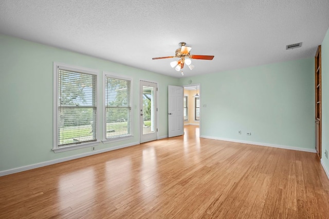 spare room with a textured ceiling, light wood-style flooring, and baseboards