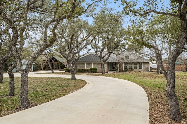 view of front of property with a front yard, a standing seam roof, brick siding, and driveway