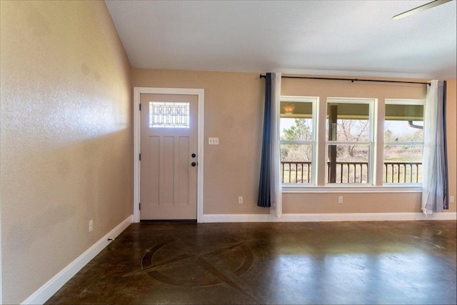 entrance foyer with a wealth of natural light, finished concrete flooring, and baseboards