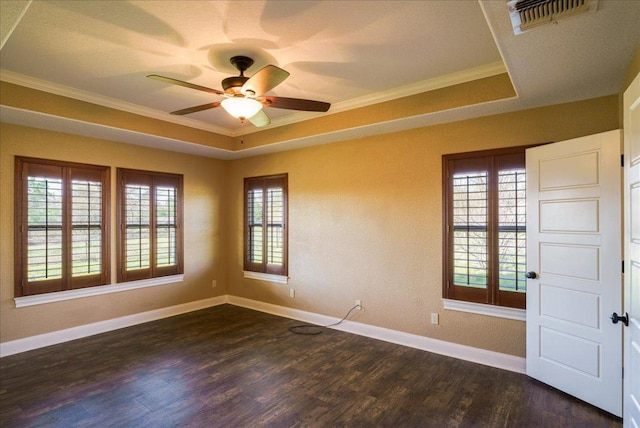 spare room with dark wood finished floors, a raised ceiling, visible vents, and a healthy amount of sunlight