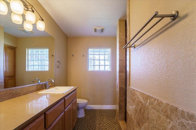 bathroom with visible vents, toilet, vanity, tile patterned flooring, and baseboards