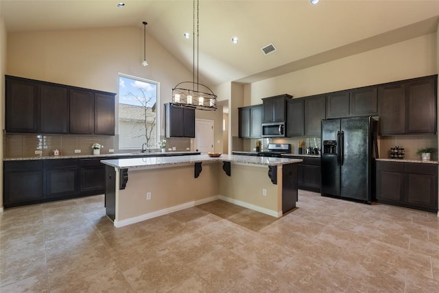 kitchen with high vaulted ceiling, stainless steel appliances, a kitchen island, visible vents, and a kitchen breakfast bar