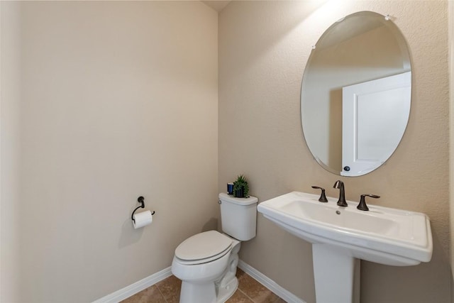 bathroom with baseboards, a sink, toilet, and tile patterned floors