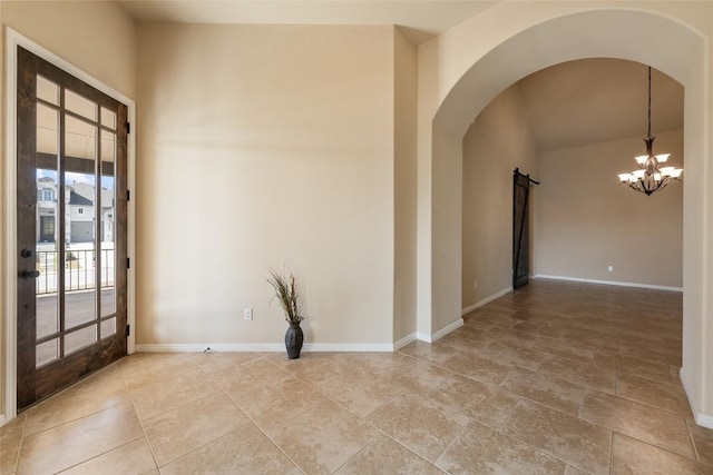 spare room featuring baseboards, arched walkways, and an inviting chandelier