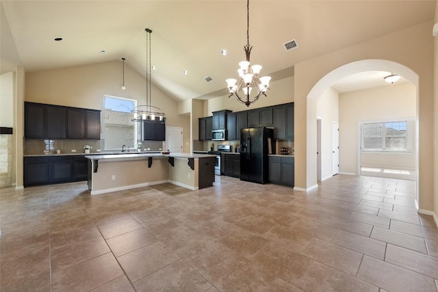 kitchen with a center island with sink, a breakfast bar area, stainless steel appliances, visible vents, and high vaulted ceiling