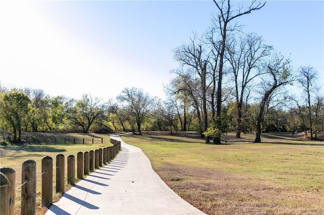 view of property's community featuring a lawn and fence