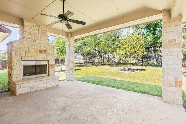 114 Darst Ln, Bastrop, TX 78602 - fenced backyard with an outdoor stone fireplace, a patio, and a ceiling fan