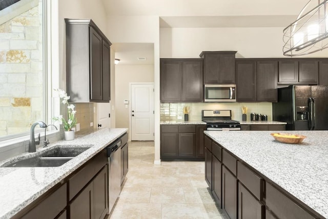 114 Darst Ln, Bastrop, TX 78602 - kitchen with stainless steel appliances, backsplash, dark brown cabinetry, and light stone countertops