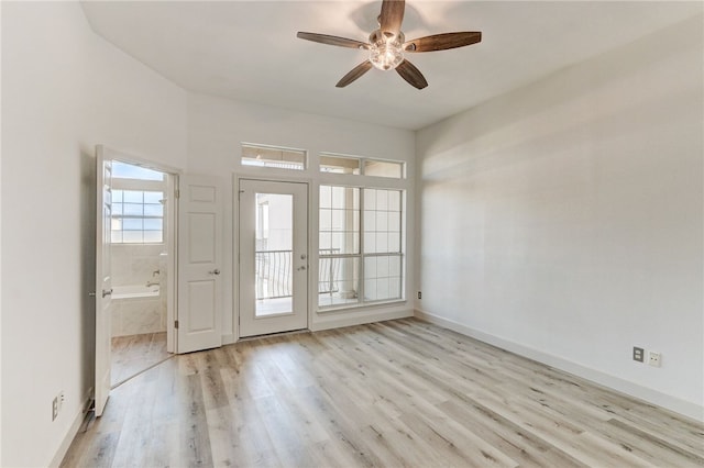 empty room with light wood-style floors, a ceiling fan, and baseboards
