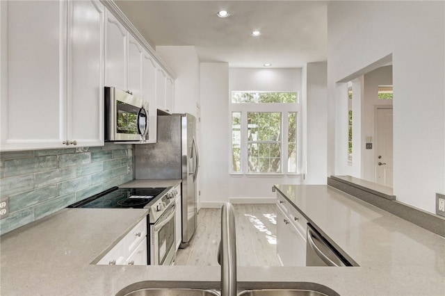 kitchen with stainless steel appliances, white cabinetry, a sink, decorative backsplash, and recessed lighting