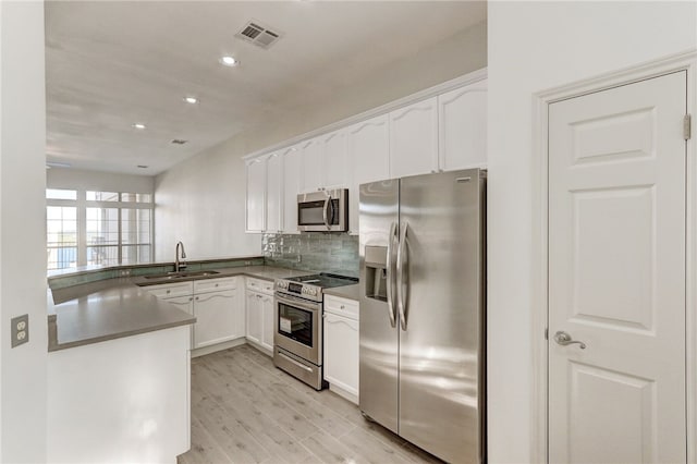 kitchen featuring stainless steel appliances, a sink, white cabinetry, light wood finished floors, and recessed lighting