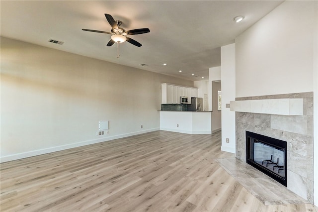 unfurnished living room with a tile fireplace, light wood-type flooring, ceiling fan, baseboards, and recessed lighting