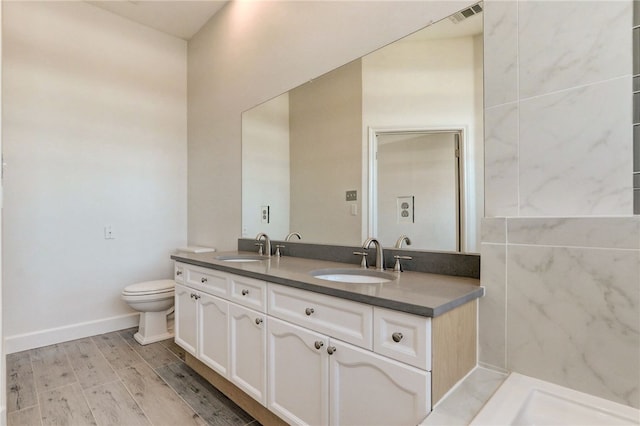 bathroom featuring toilet, double vanity, and baseboards