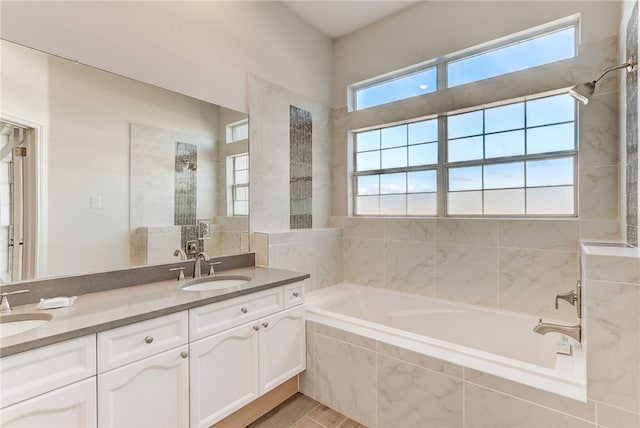 bathroom with tiled tub, tiled shower, and double vanity