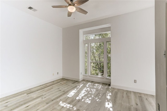 spare room with wood finished floors, a ceiling fan, and baseboards