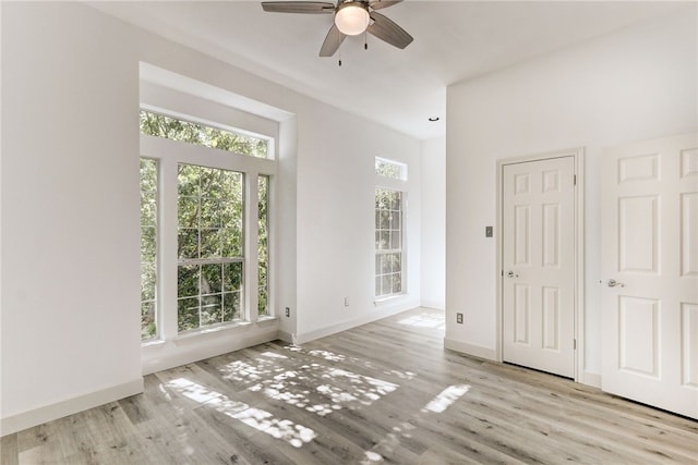 unfurnished room with ceiling fan, wood finished floors, and baseboards