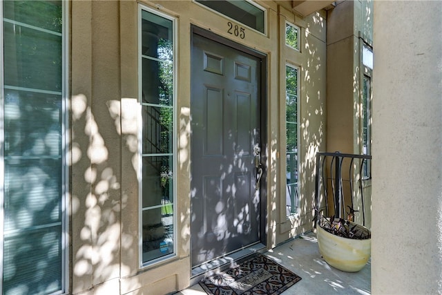 doorway to property featuring stucco siding and a porch