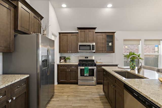 kitchen with stainless steel appliances, backsplash, a sink, and dark brown cabinetry