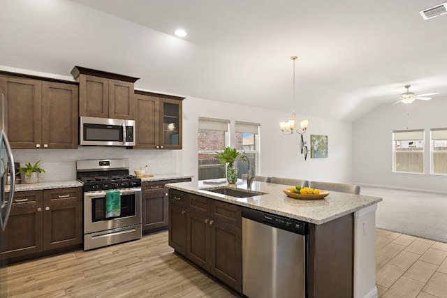 kitchen with stainless steel appliances, visible vents, open floor plan, vaulted ceiling, and a sink