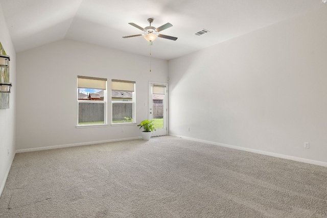 empty room with baseboards, visible vents, a ceiling fan, lofted ceiling, and carpet flooring