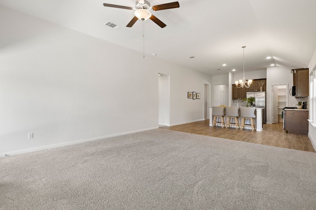 unfurnished living room featuring light carpet, ceiling fan with notable chandelier, visible vents, and recessed lighting