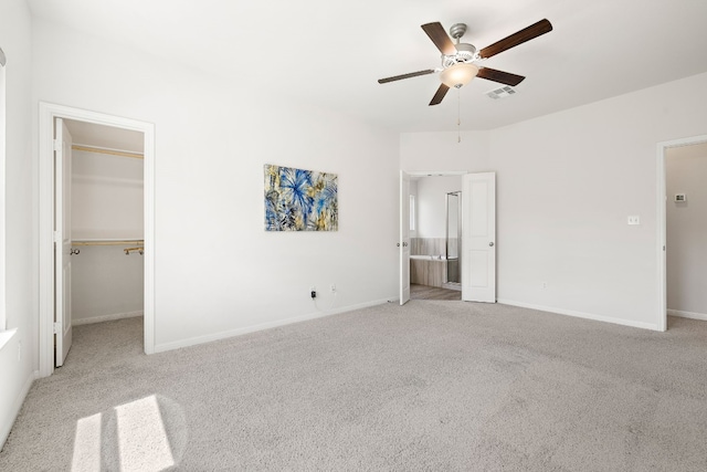 unfurnished bedroom with visible vents, baseboards, a ceiling fan, carpet, and a walk in closet