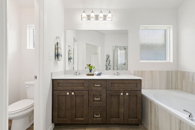 bathroom with a garden tub, a stall shower, a sink, and toilet