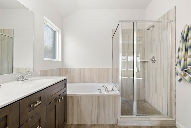 bathroom with lofted ceiling, a shower stall, a bath, and vanity