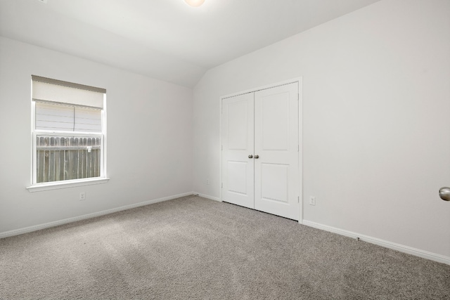 unfurnished bedroom with carpet, baseboards, and vaulted ceiling